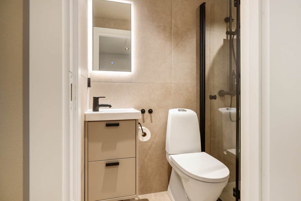 Sleek Modern Bathroom Refresh in style with a sparkling clean en-suite featuring a glass shower, contemporary fixtures & warm wood-tone finishes — spa-like comfort in central Bergen!