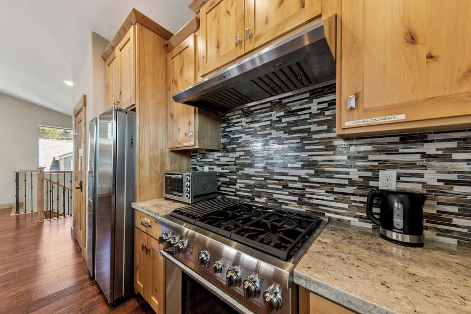 You'll love preparing meals in this inviting kitchen, featuring warm natural wood cabinetry, gleaming stainless appliances, and stylish modern tile backsplash. Everything you need to feel right at home.