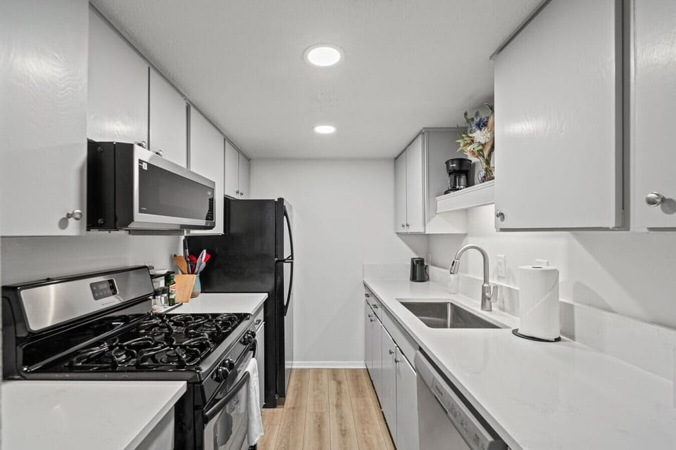 Cook with ease in the updated galley kitchen, featuring a gas range, full-size fridge, and crisp quartz counters with ample storage.