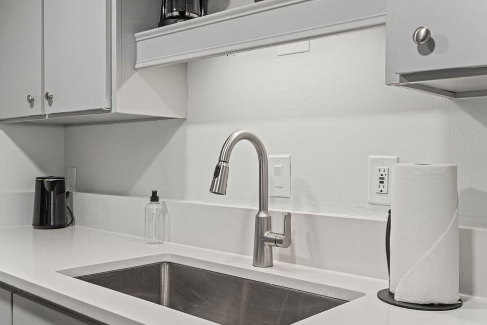 A deep stainless sink with a pull-down faucet sits at the center of bright quartz countertops, keeping meal prep easy and clean.