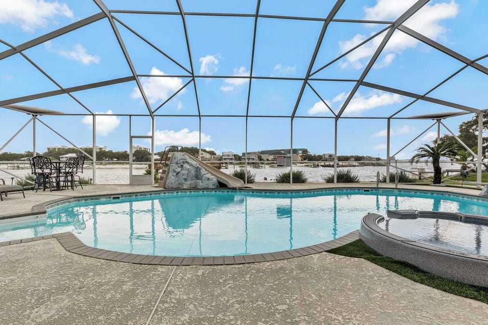 The expansive screened pool deck offers generous lounge space for sunbathing or relaxing in the shade, all within a bug-free enclosure. It's a resort-style outdoor area built for entertaining large groups at this Pensacola-area waterfront rental.
