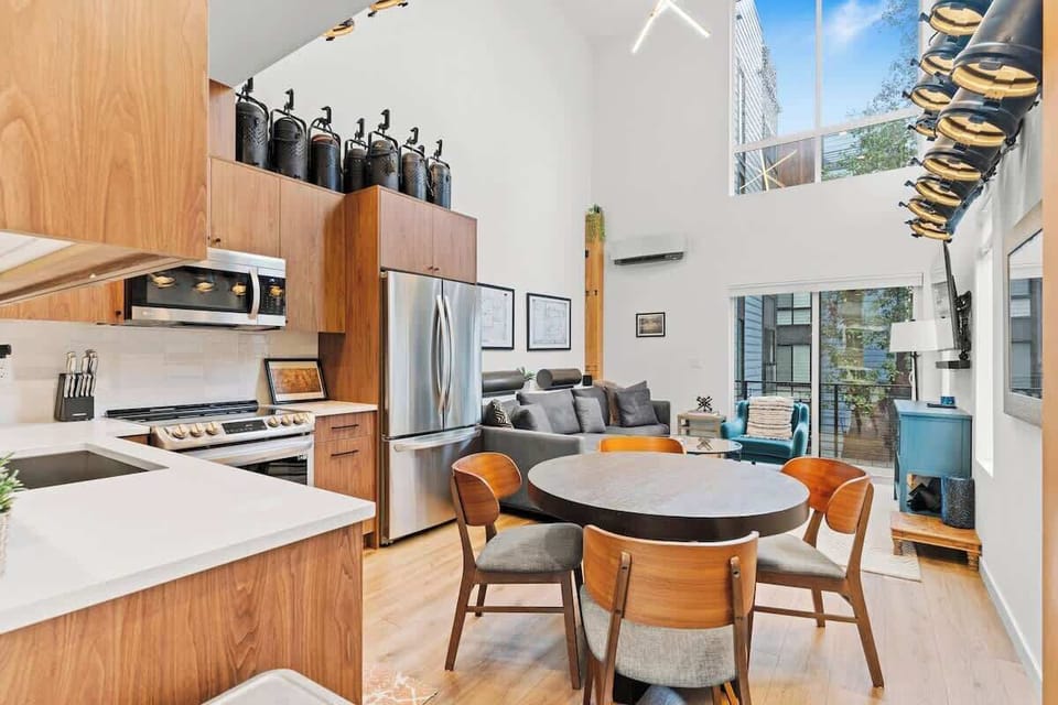 Open living space with double-height loft ceilings, exposed wood beams, and reclaimed theater lighting installation from Seattle's Moore Theater