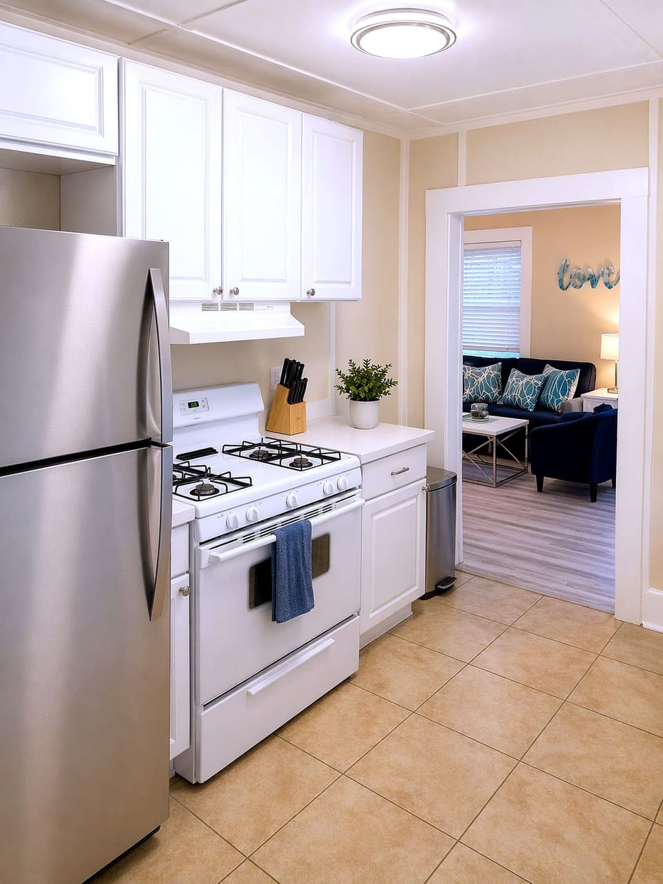 Bright kitchen with gas range, stainless fridge; cozy lounge beyond