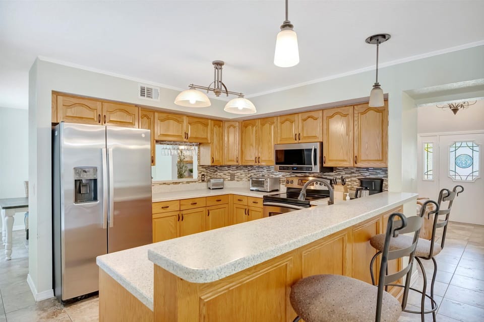 Full kitchen featuring granite countertops, stainless steel appliances, and bar seating.