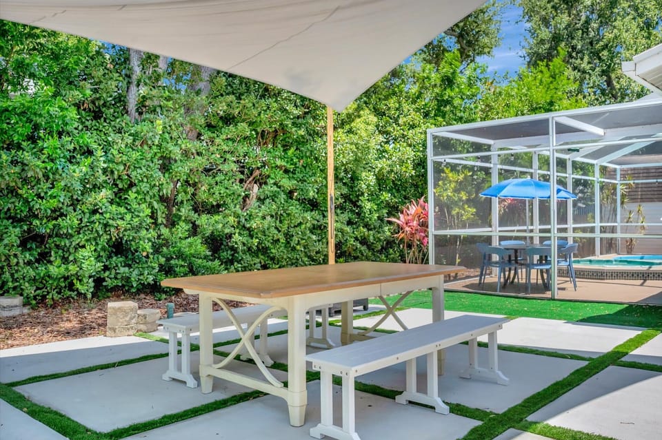 Covered patio with picnic-style dining table overlooking the pool enclosure.