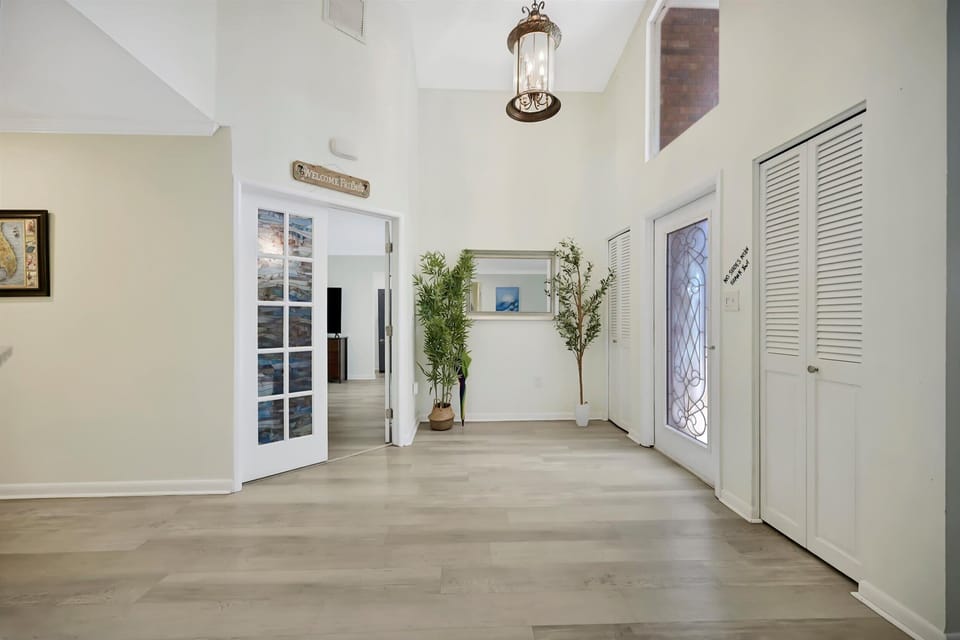 Grand entry foyer with high ceilings and double glass doors to one of the bedrooms