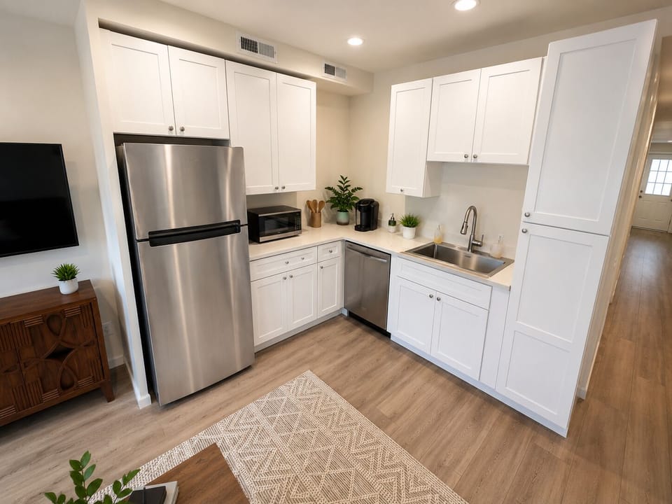 Bright full kitchen with white cabinetry, stainless steel appliances, dishwasher, and ample storage.