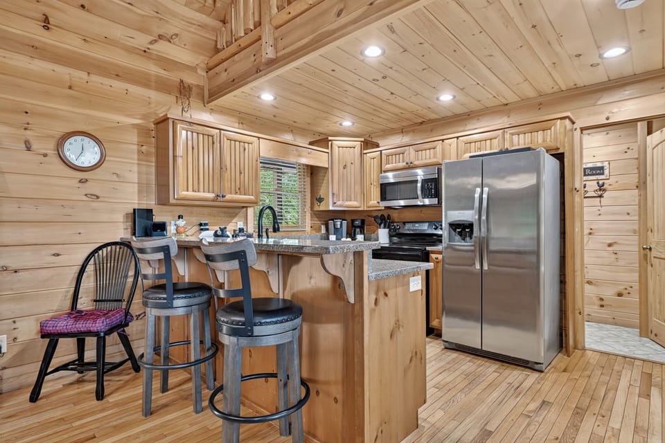 The fully stocked kitchen features stainless steel appliances, granite countertops, and bar seating, giving you everything needed to prepare meals during your Georgia mountain vacation