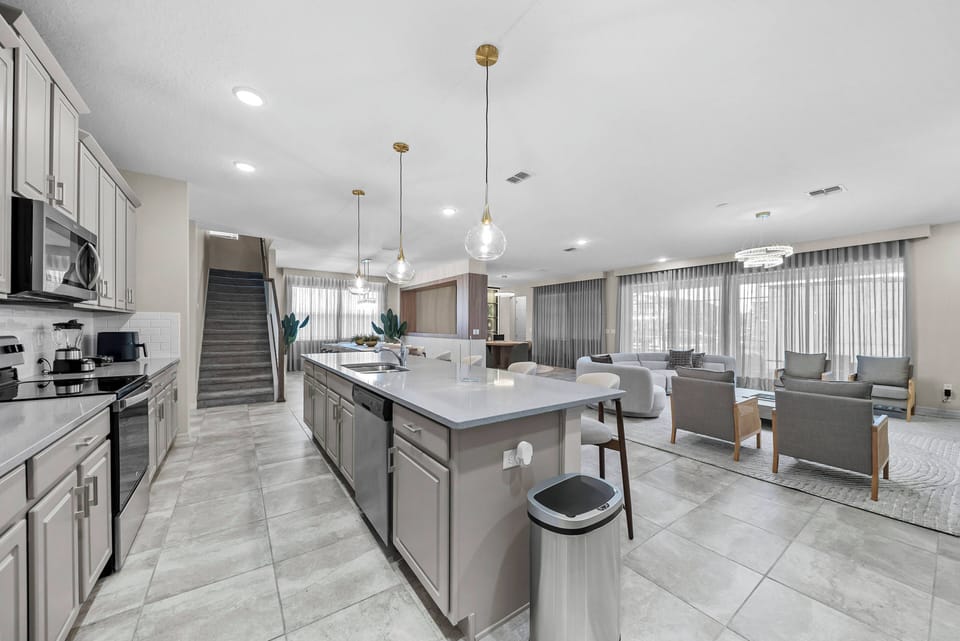 Experience a bright kitchen with modern gray cabinetry and a lovely island with bar seating, ideal for casual meals. Large windows fill the space with natural light, creating a warm atmosphere that flows into the spacious living.