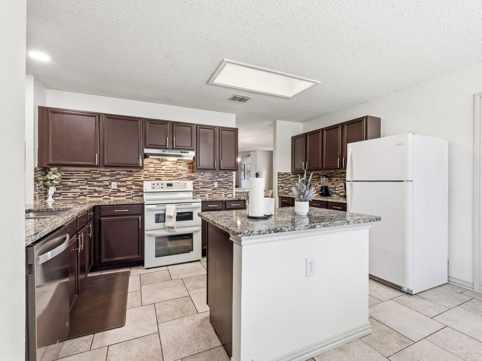 Prepare meals in a well-equipped kitchen with granite counters, stylish tile backsplash, and stainless appliances that make cooking a pleasure during your stay.