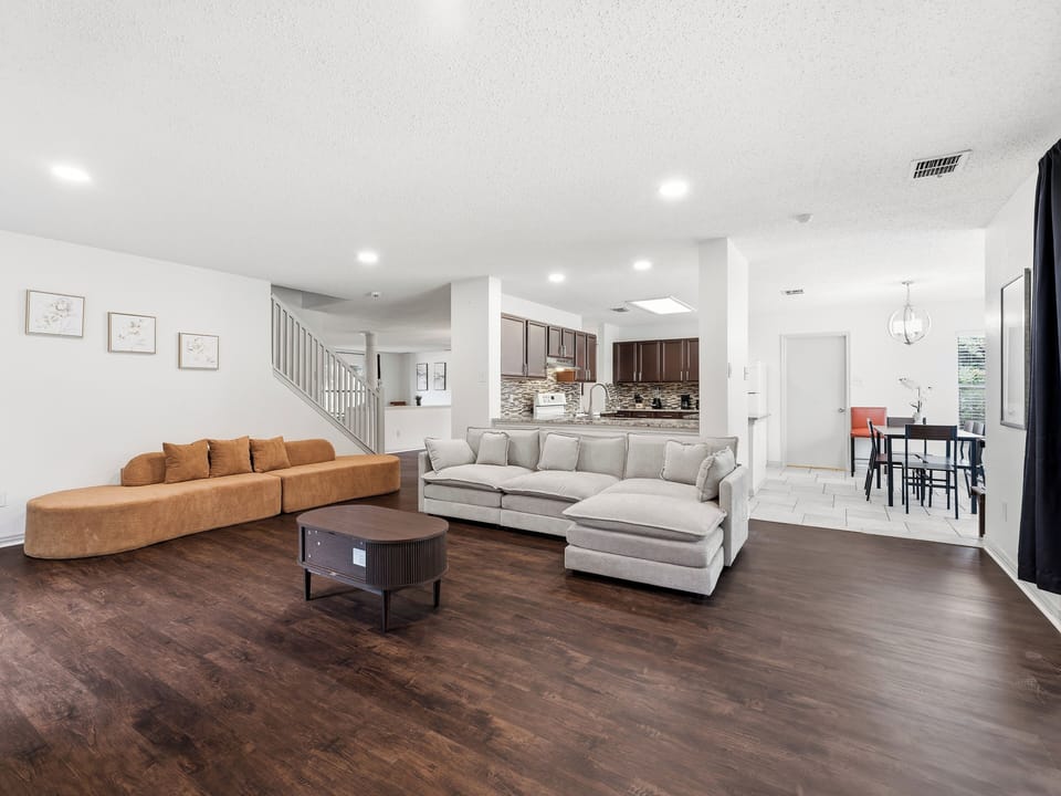 Unwind in your spacious living area, where modern design meets comfort. Plush sofas, rich wood floors, and an open layout to the kitchen create a welcoming space for relaxation and connection.