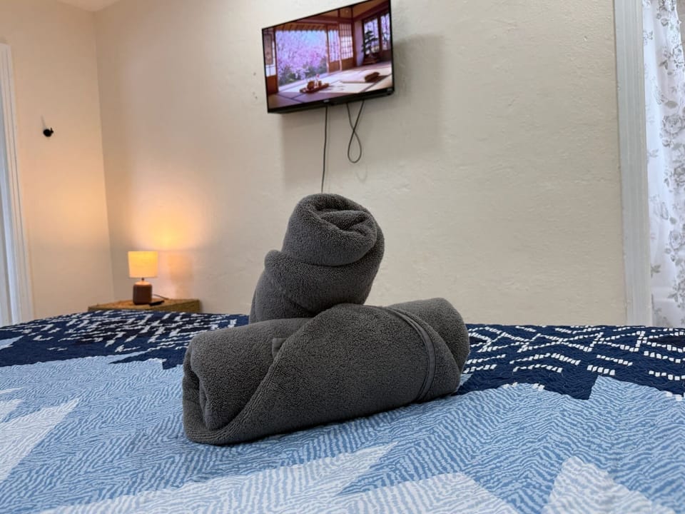 Cozy bedroom with wall-mounted TV, warm lighting, and fresh towels