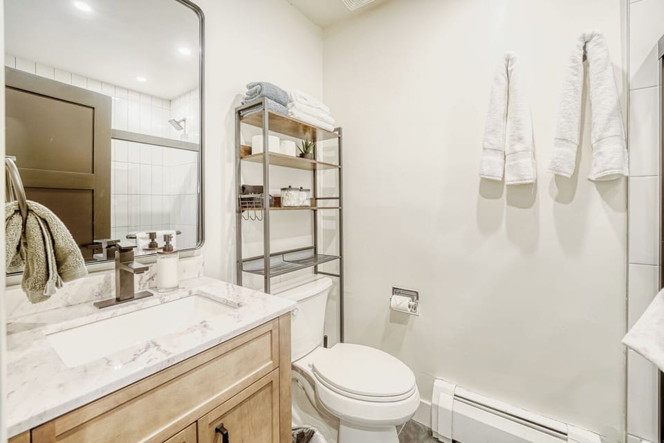 Clean, bright, and thoughtfully designed 🛁. This shared hallway bathroom features a tub with glass doors—perfect for a quick refresh or a relaxing soak