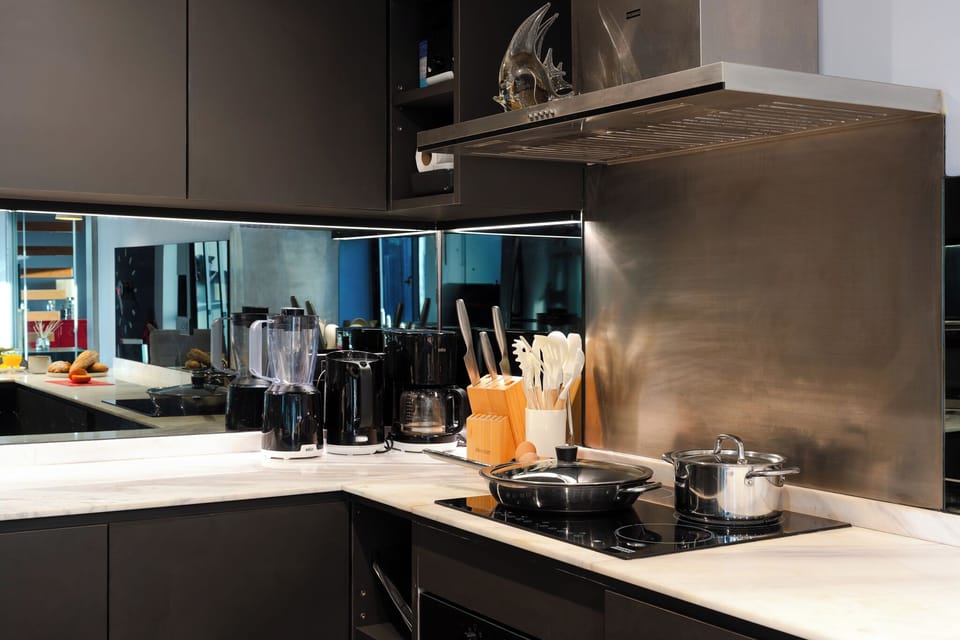 【The Full Kitchen】Franke cooktop, hood, oven, and dishwasher along one wall. Electrolux fridge, freezer, and microwave handle a long-stay grocery load. Built so you cook a few real meals a week.
