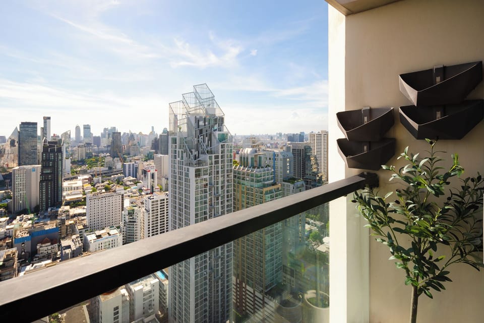 【Open Balcony】High enough above traffic that the open window stays usable at any hour. Best in the early evening when the city light is warm. AC off, curtains tied back, the city in the room.