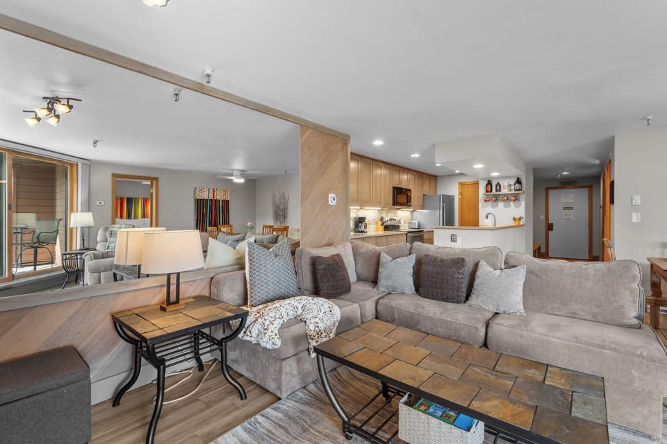 Step into your spacious open-plan living area with plush seating, warm wood accents, and a fully-equipped kitchen ready for your mountain getaway.