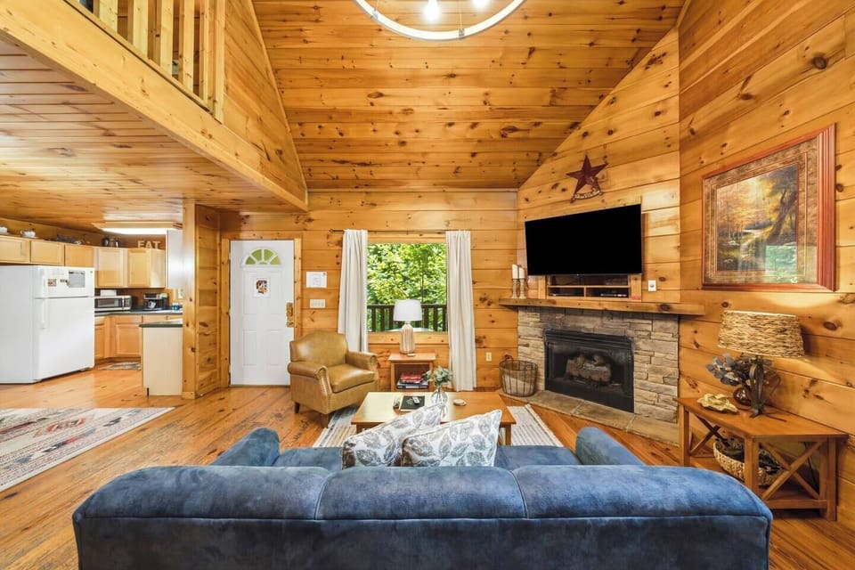 Cozy cabin great room with stone fireplace, loft, and open-concept living