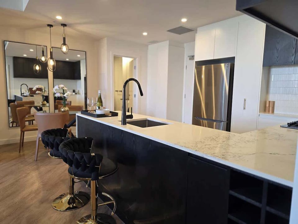 Designer Kitchen — Premium Finishes and Golden Bar Stools. Share a wine with friends.
