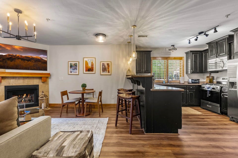 Relax in your beautifully appointed open-plan living space, where warm wood floors, elegant cabinetry, and a cozy fireplace create the perfect setting for unwinding after a day of mountain adventures.