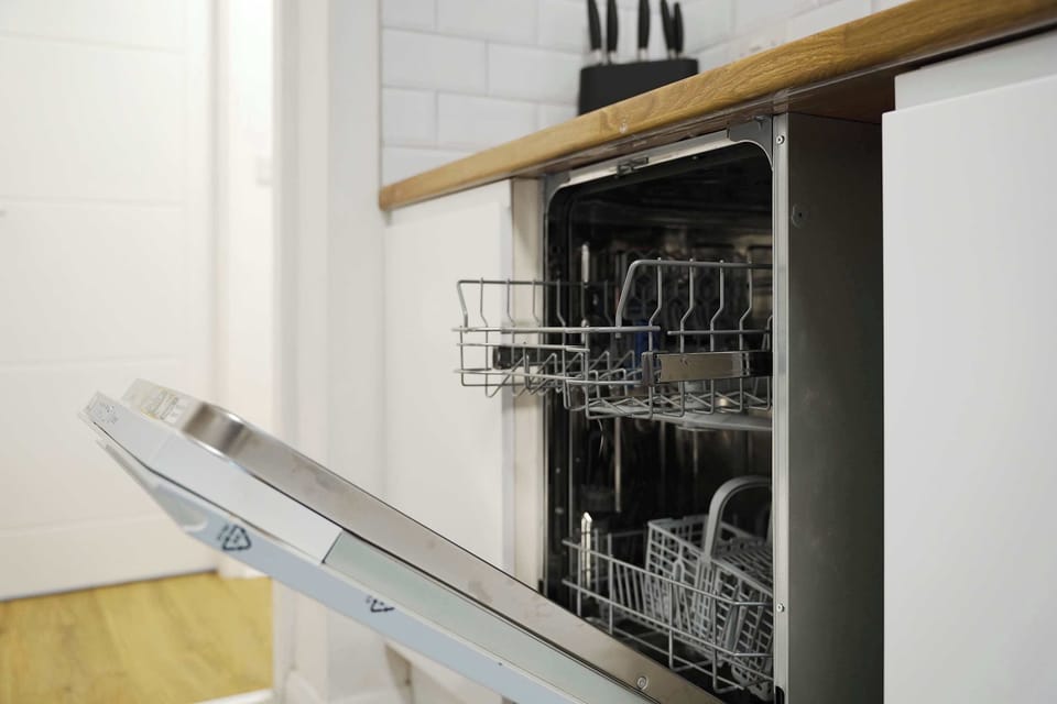 Equipped with a fridge/freezer, oven, hob, sink, dishwasher, and storage cupboards for kitchen essentials and cleaning supplies, the kitchen also provides access to the backyard.