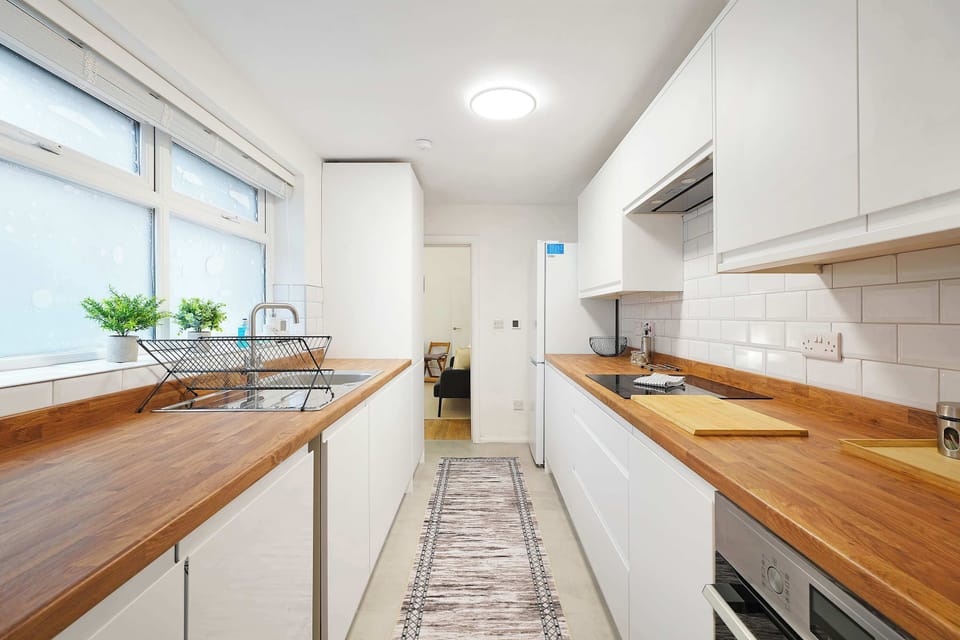 Featuring a fridge/freezer, oven, hob, sink, dishwasher, and practical storage, the kitchen offers space for utensils, pots, pans, and cleaning supplies, with direct access to the backyard.