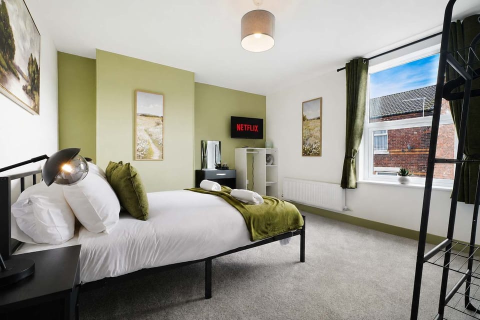 This first double bedroom offers a double bed, TV, dresser, two bedside tables, and storage space. The room's cupboard houses the boiler, clothes dryer, iron, ironing board, and vacuum.