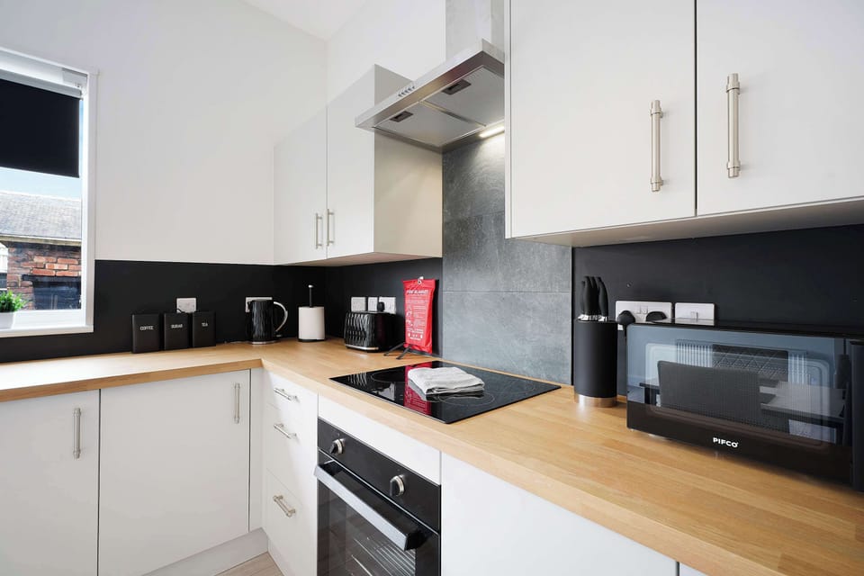 This well-equipped kitchen offers a four-seater dining table, fridge freezer, washing machine, oven, hob, microwave, sink, and everyday kitchen essentials. It also leads to the backyard.