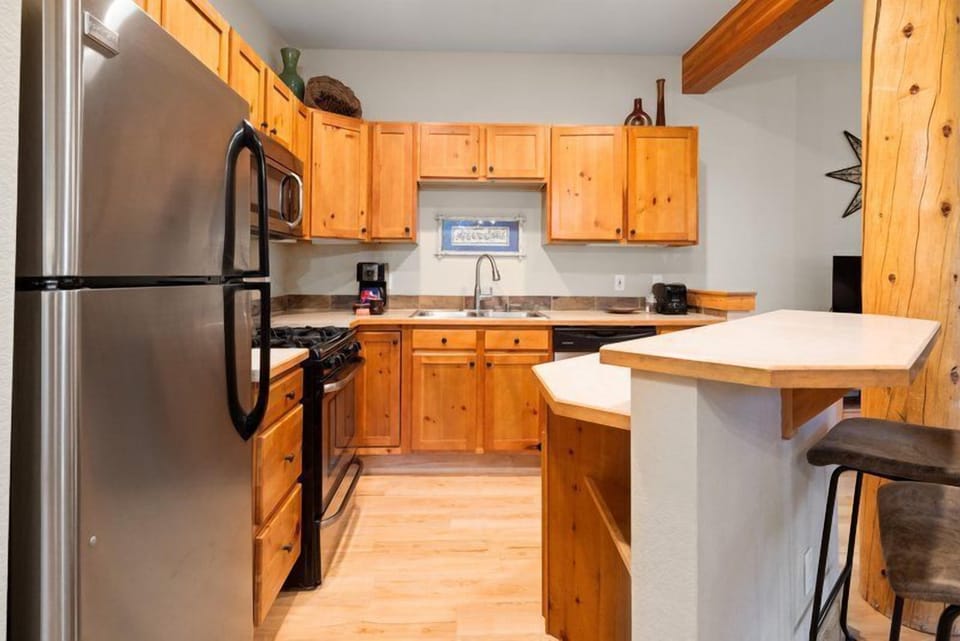 The fully-equipped kitchen boasts warm wooden cabinets and modern appliances, perfect for preparing delicious meals during your mountain getaway.