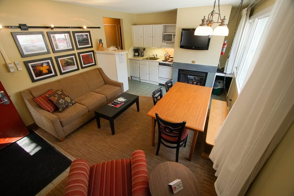 Gather around the fireplace, where warmth meets comfort in an inviting living and dining space.