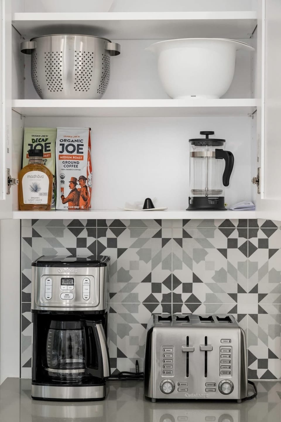 Kitchen pantry cabinet stocked with coffee, tea, sugar, honey, EVOO, balsamic vinegar, and spices. 