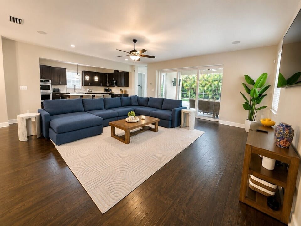 Gather, relax, and unwind in our oversized open-concept living room featuring a plush sectional, Smart TV, and seamless access to the covered lanai, heated pool, and fully stocked kitchen.