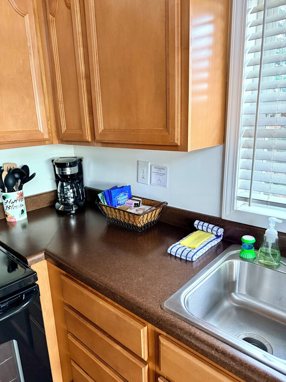 Bright, stocked kitchen with coffee station and sunny sink view.