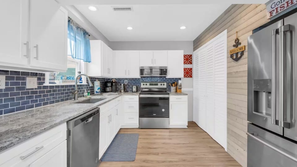 Fully equipped kitchen with stainless steel appliances, white cabinetry.