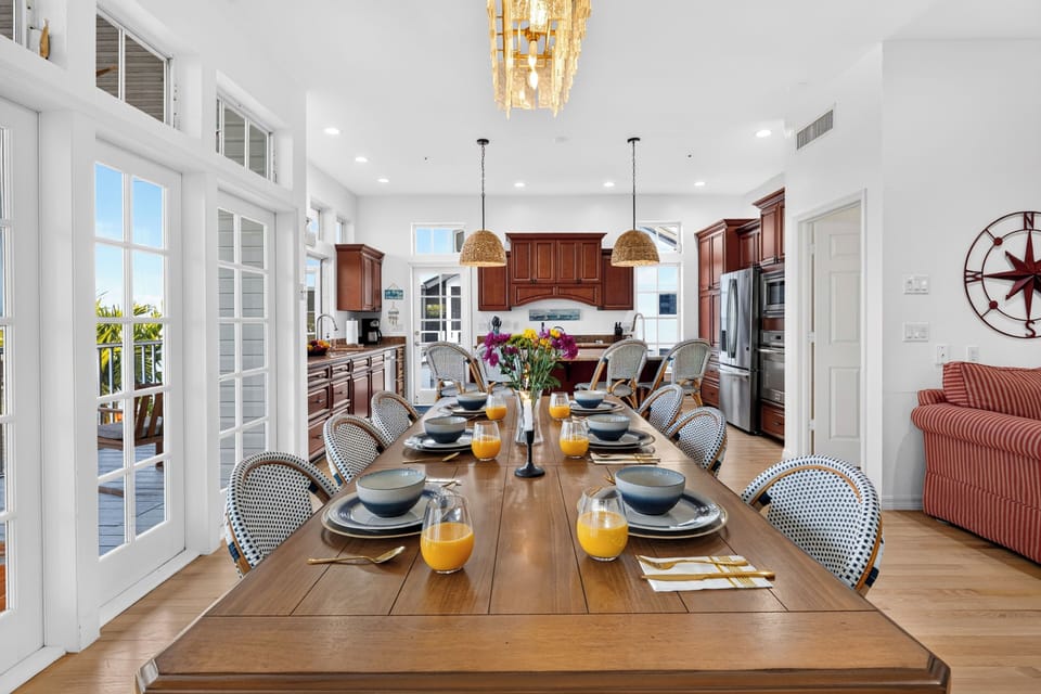 This grand dining space offers an expansive table setting beneath dual decorative lighting fixtures.