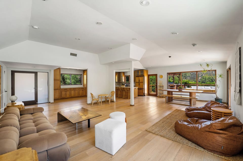 Open-concept living, dining, and kitchen area with warm wood floors, relaxed seating, and mountain-view windows.