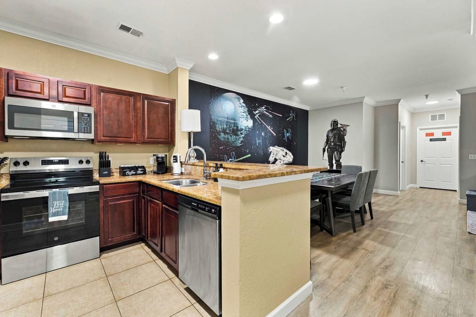 Step past the life-sized welcoming droids you’re looking for into the space cantina full kitchen, with warm red-and-brown stone countertops, stainless and black appliances, sci-fi-inspired small appliances, a complimentary coffee/tea bar, 