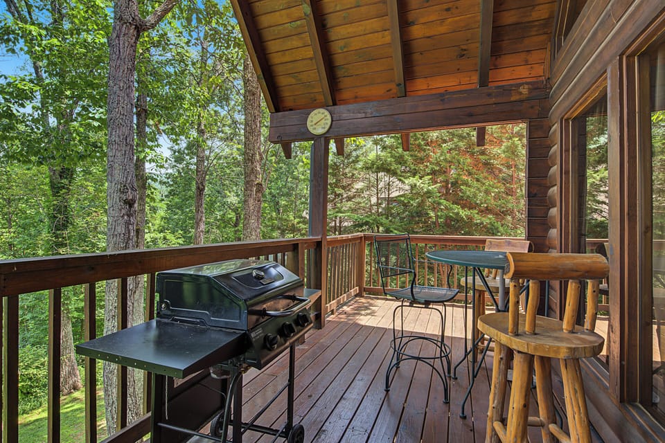 A covered deck nestled among towering trees, where you can grill, dine, and unwind surrounded by nature's peaceful embrace and fresh forest air.