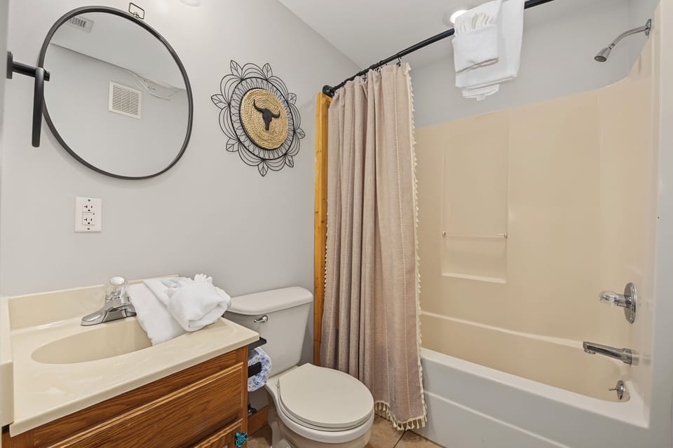Step into your private retreat, where a sleek circular mirror and charming wall art add personality. Crisp towels await, and the tub/shower combo invites you to unwind after a day of adventure.