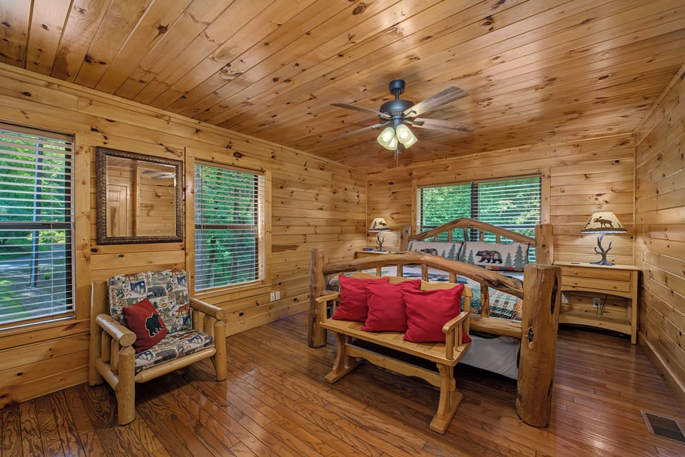 Unwind in this inviting bedroom with rustic wood paneling and handcrafted log furniture. Cozy lamps and a gentle ceiling fan create the perfect retreat after your mountain adventures.