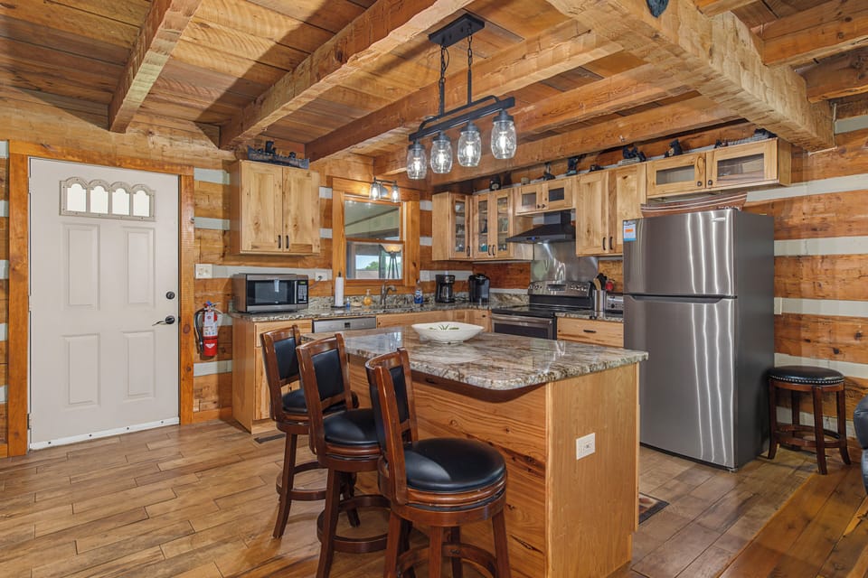 Your fully equipped cabin kitchen has everything you need, from granite countertops and modern appliances to a cozy island with bar seating—perfect for morning coffee or meal prep together.