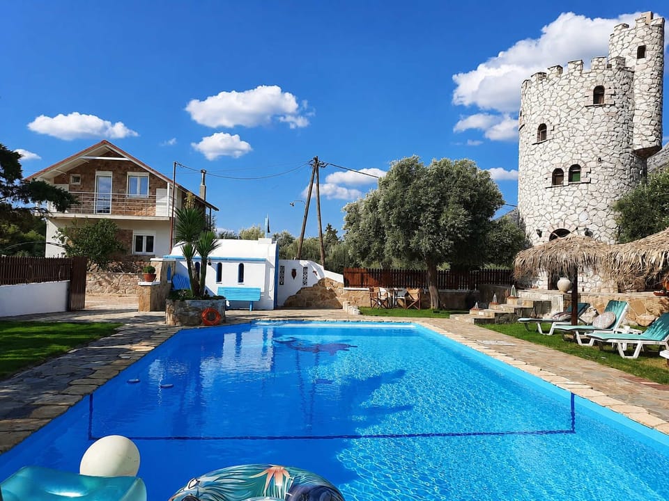 A sunny pool view with the stone tower, blue water, and a relaxed courtyard atmosphere. A great spot for swimming, reading, or just enjoying the quiet
