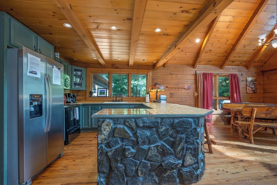 Fully stocked kitchen with bar and bar stools and dining table that seats 8-10