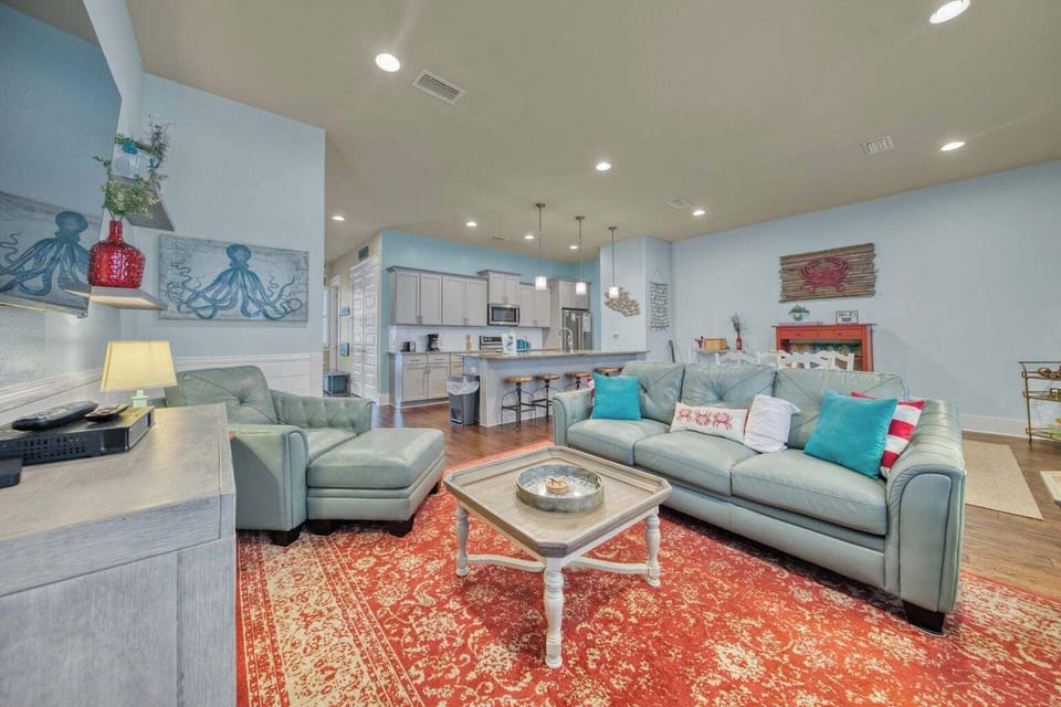 Settle into plush seating in your spacious open-concept living area, where coastal charm meets modern comfort. The fully-equipped kitchen invites you to create memorable meals together.