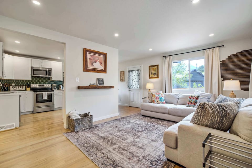 Crisp white shaker cabinets and gleaming quartz counters anchor this kitchen, flowing openly into the living and dining areas beyond. Big windows over the table frame the backyard's trees, tying the whole open concept space together.