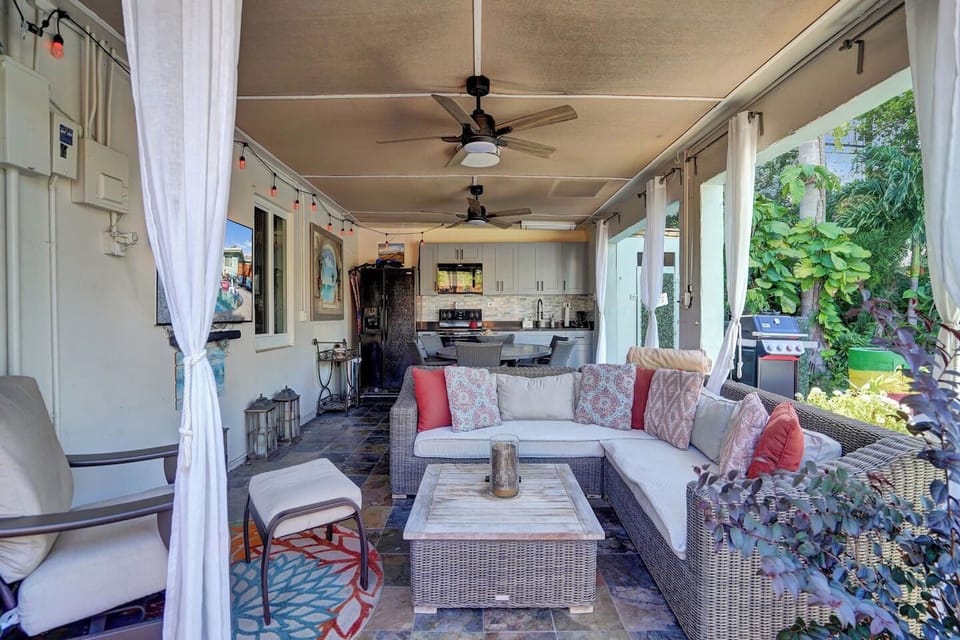 Screened lanai lounge with ceiling fans and an outdoor kitchen.