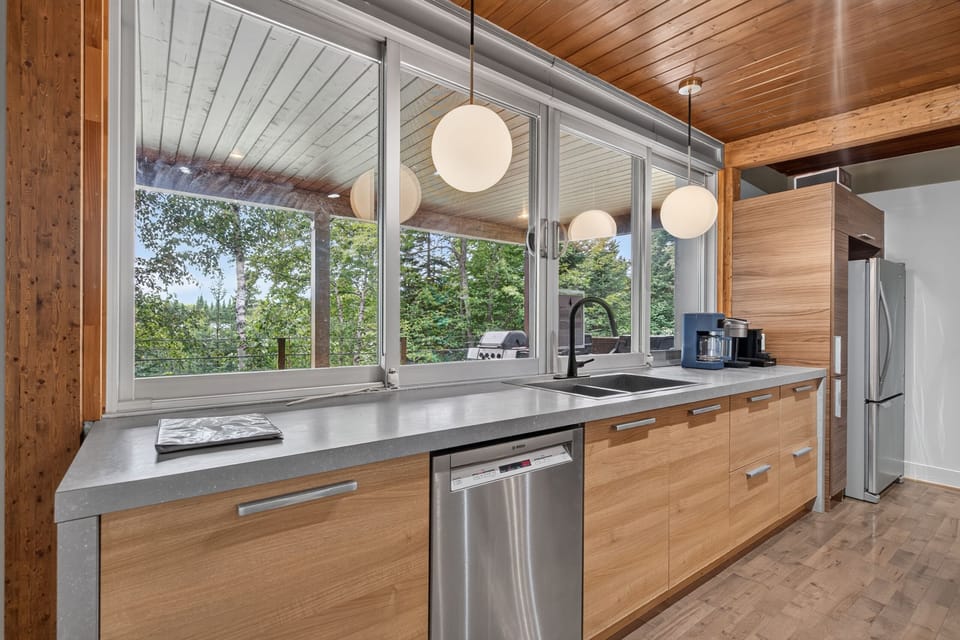 Bright modern kitchen with forest views and expansive picture windows