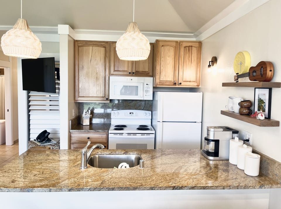 This fully equipped kitchen features granite countertops and organic textures, providing everything you need for island-inspired meals. Its open design ensures a bright, social atmosphere that flows perfectly into the dining and living spaces