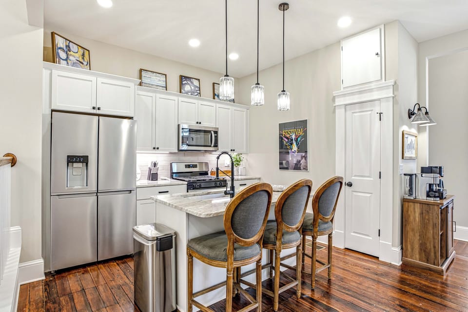 Open kitchen with stainless appliances, a gas range, island seating, and a fully stocked coffee bar.