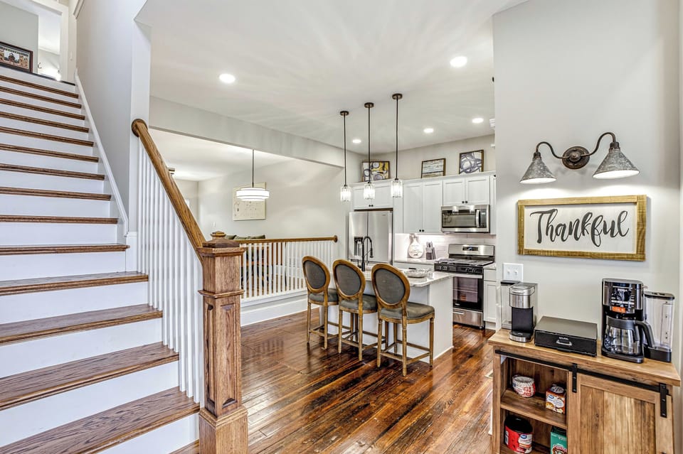 Open kitchen with stainless appliances, a gas range, island seating, and a fully stocked coffee bar.