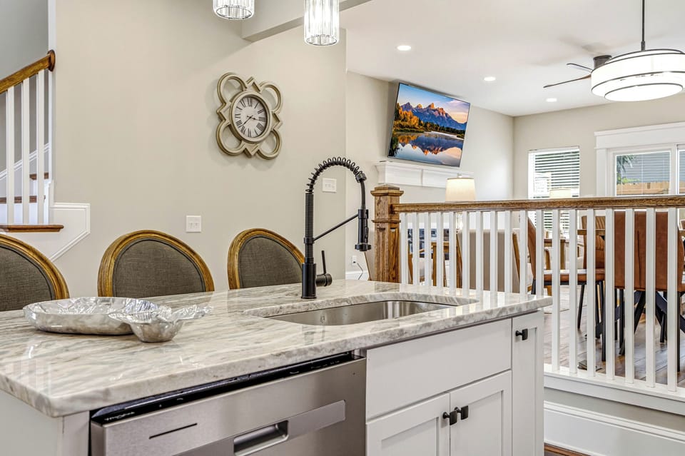Open kitchen with stainless appliances, a gas range, island seating, and a fully stocked coffee bar.